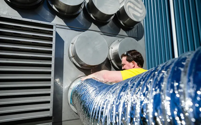 Technician connecting ducting to a mobile HVAC unit